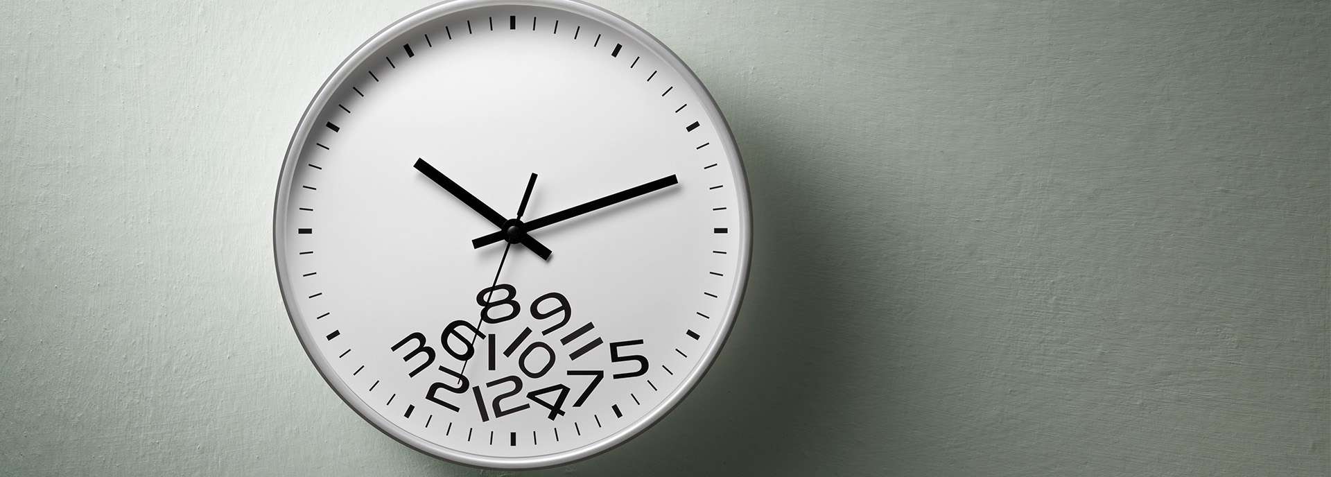 Wanduhr mit ungewöhnlicher Ziffernplatzierung auf grünem Hintergrund.