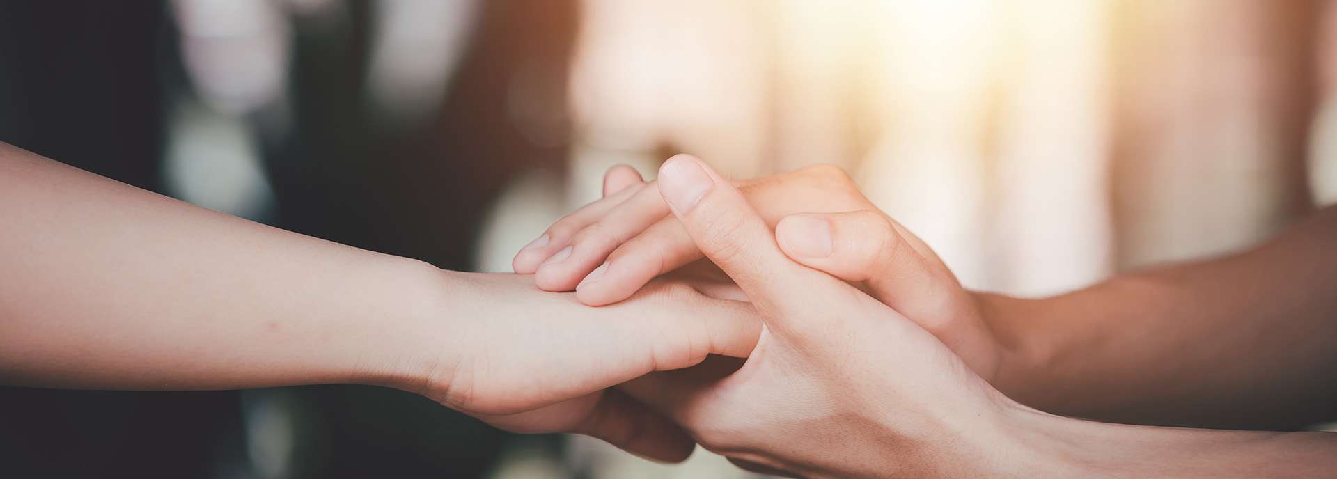 Due mani che si toccano delicatamente, simboleggiando supporto e connessione in una luce calda.