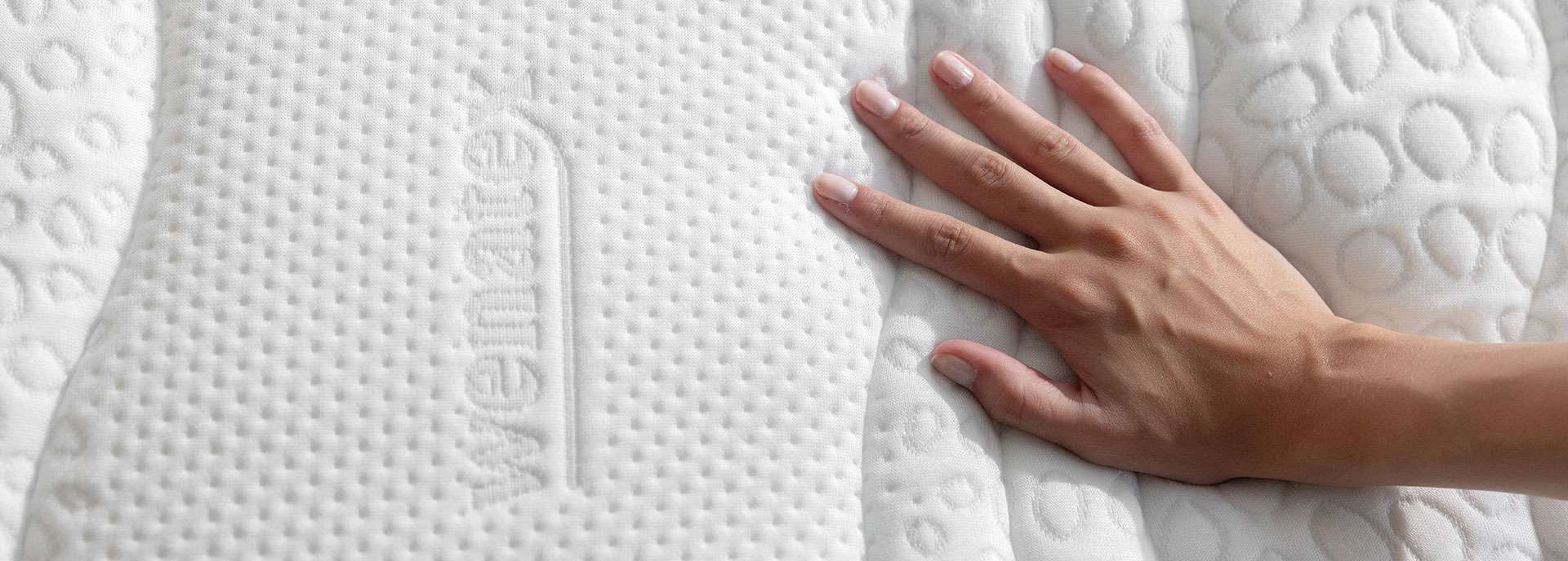 Hand berührt die Oberfläche einer Wenatex Matratze mit strukturiertem Bezug.
