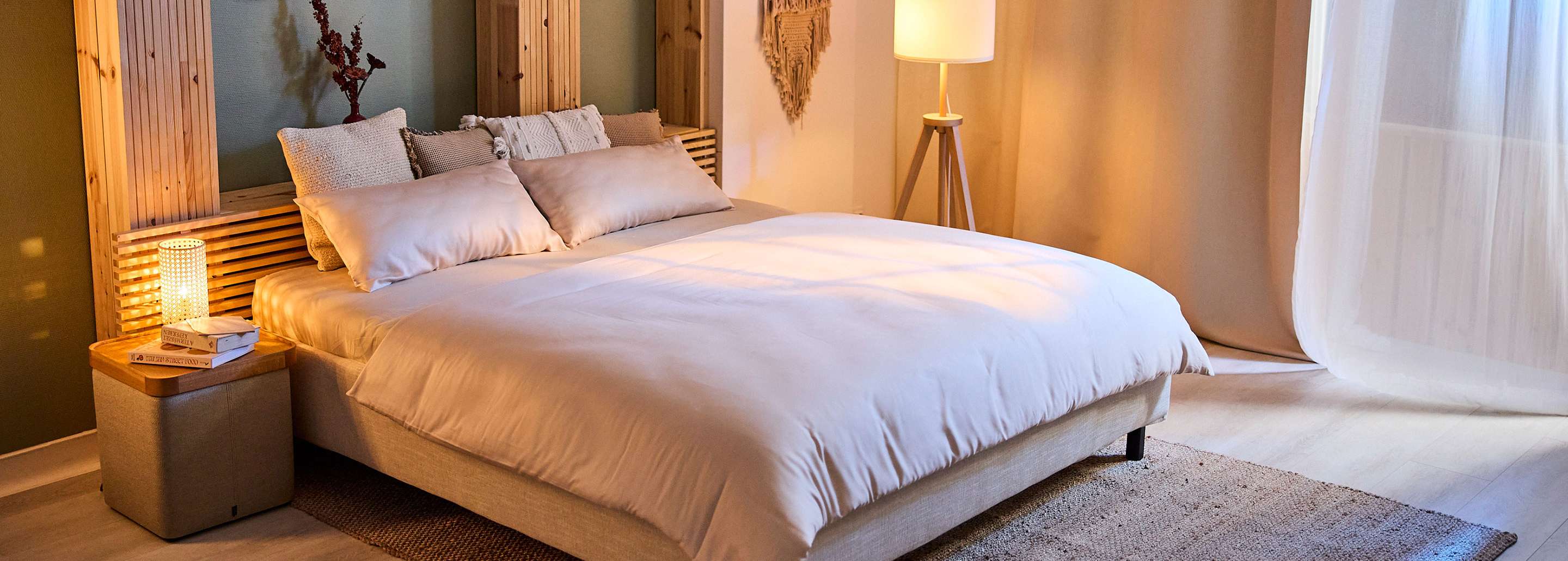 Gemütliches Schlafzimmer mit Bett, Kissen und Bettdecke in warmen Farbtönen.