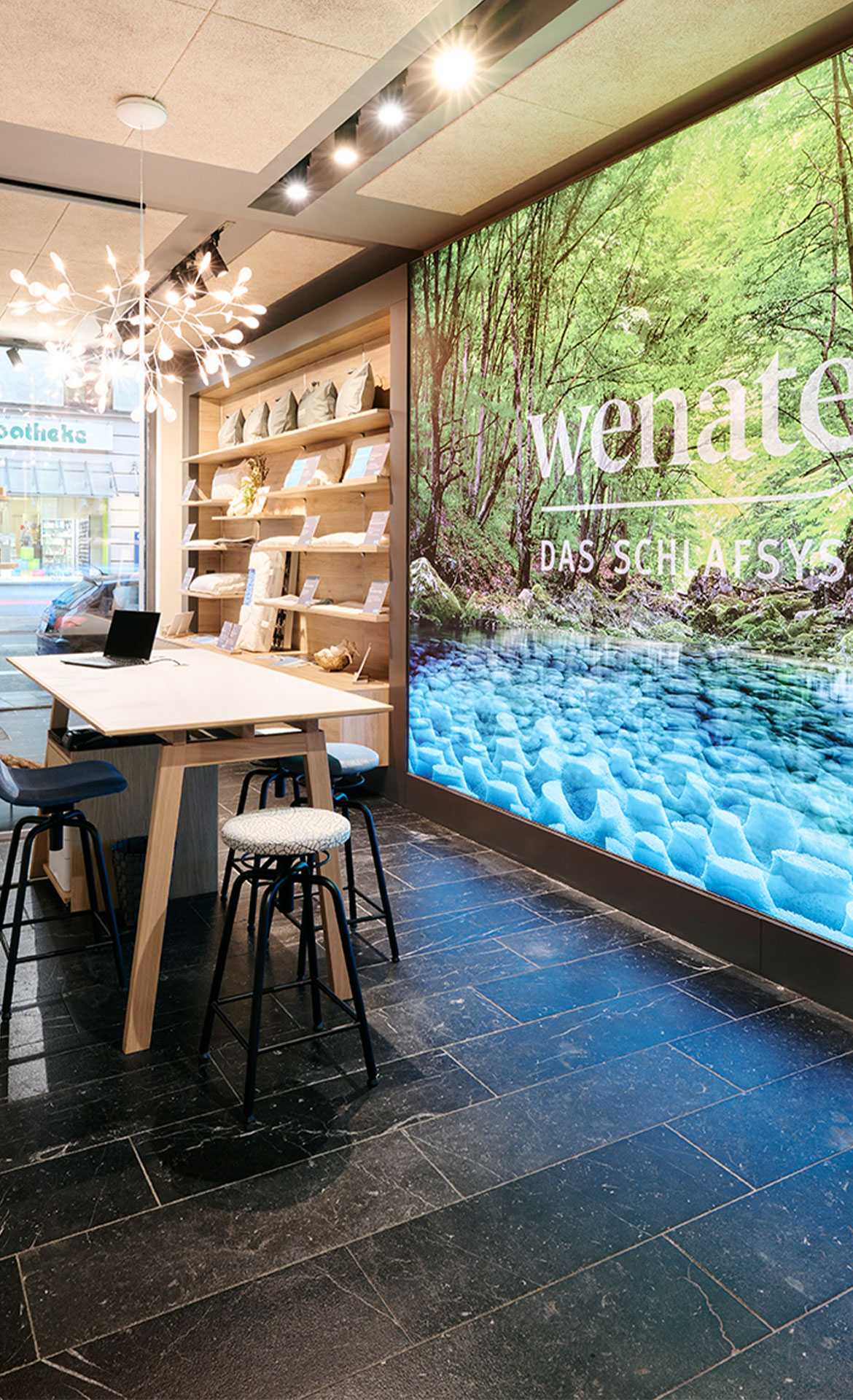 Interior view of a modern room with wooden shelves, a table, and a large wall featuring a nature motif.