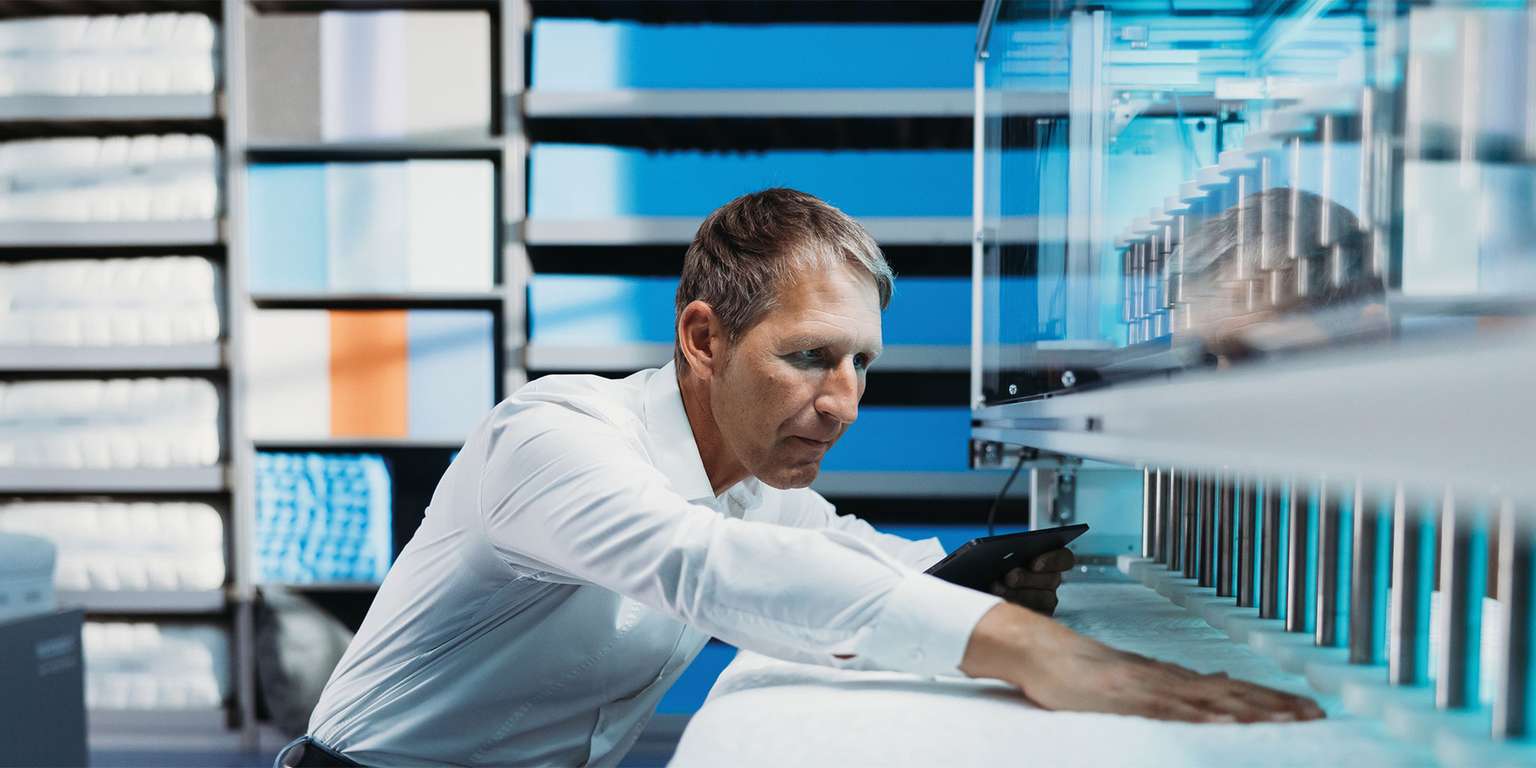 Ein Mann überprüft die Qualität von Matratzen in einem modernen Produktionsumfeld von Wenatex.