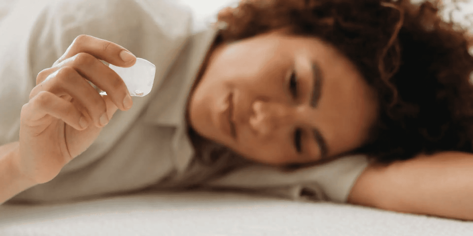 Woman relaxing on a lounge chair holding an ice cube in her hand.