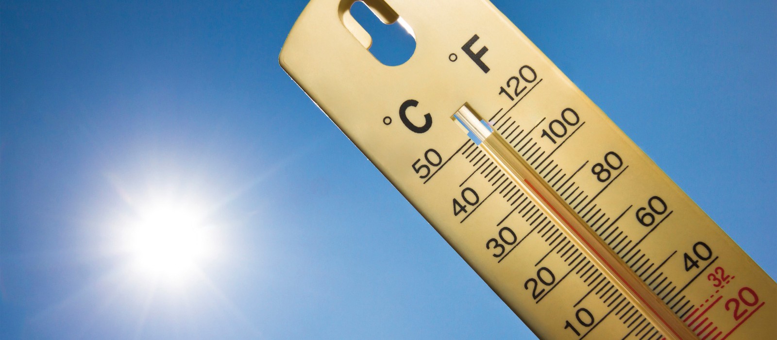 Termometro che segna alte temperature sotto un cielo blu brillante, perfetto per notti estive e sonno riposante.