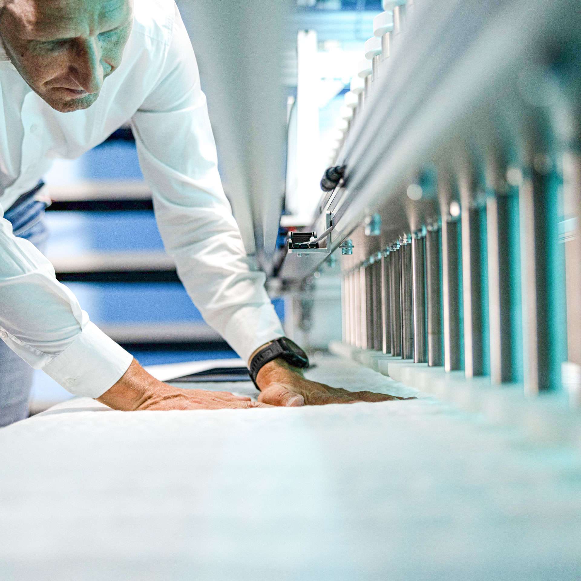 Ein Mann arbeitet an einer Maschine zur Herstellung von Matratzen, die Qualität und Präzision betont.