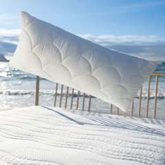 Kissen schwebt über Bett am Strand