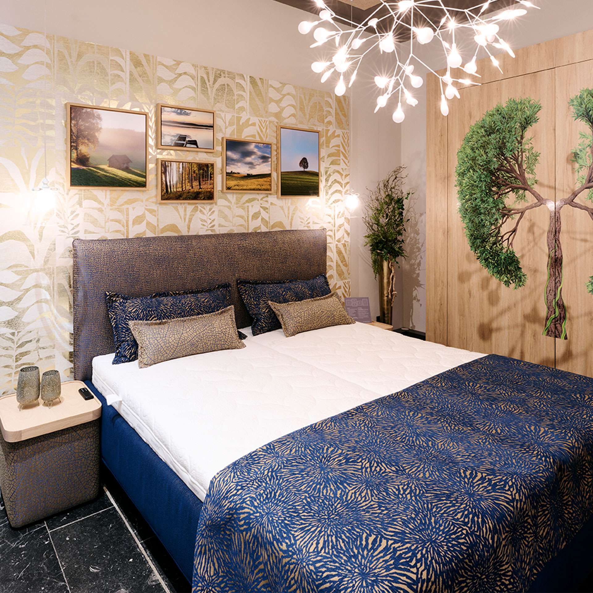 Bedroom with a double bed, decorative cushions, modern lamps, and a wall featuring plant motifs.