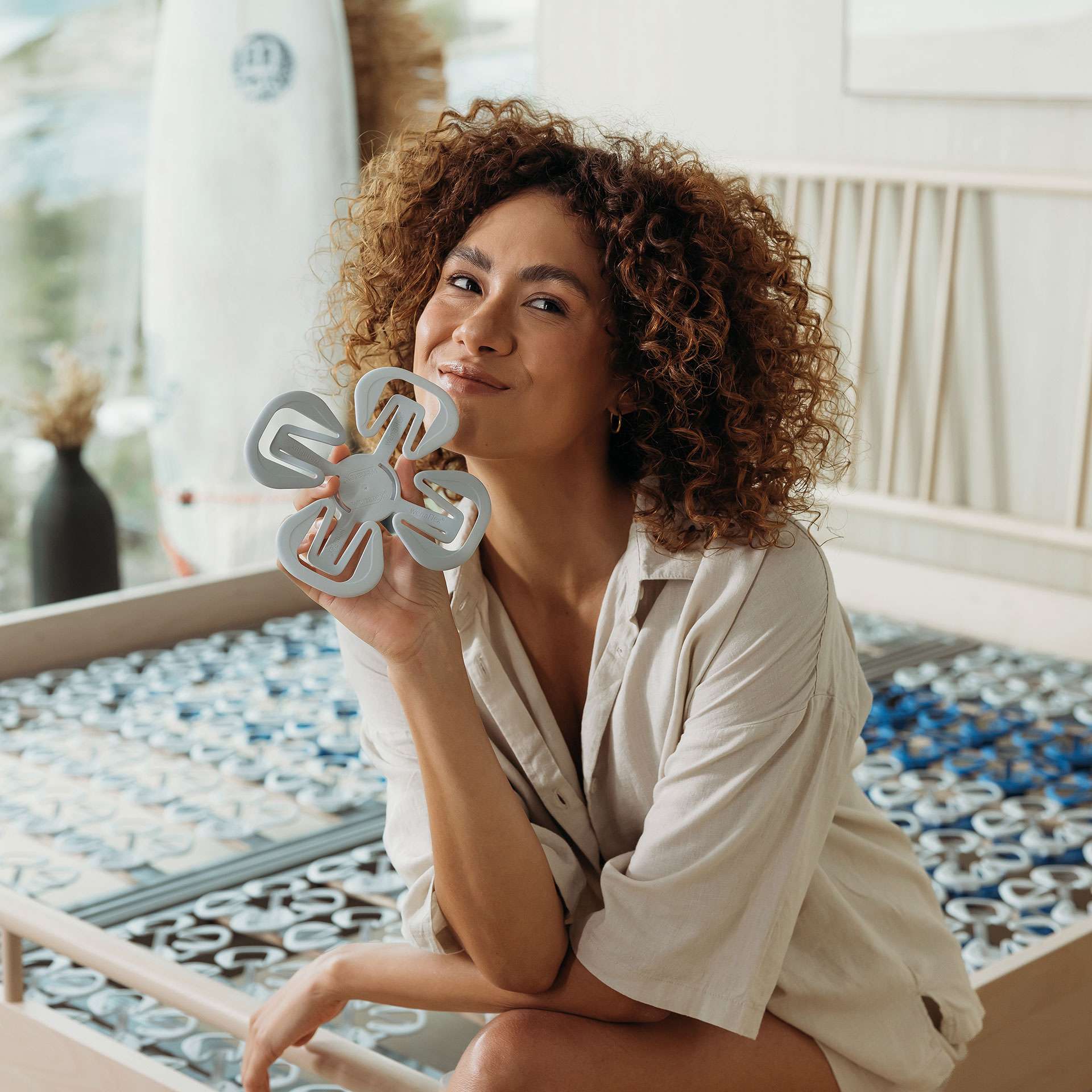 Woman holding an innovative product, sitting on a bed with a Wenatex slatted frame.