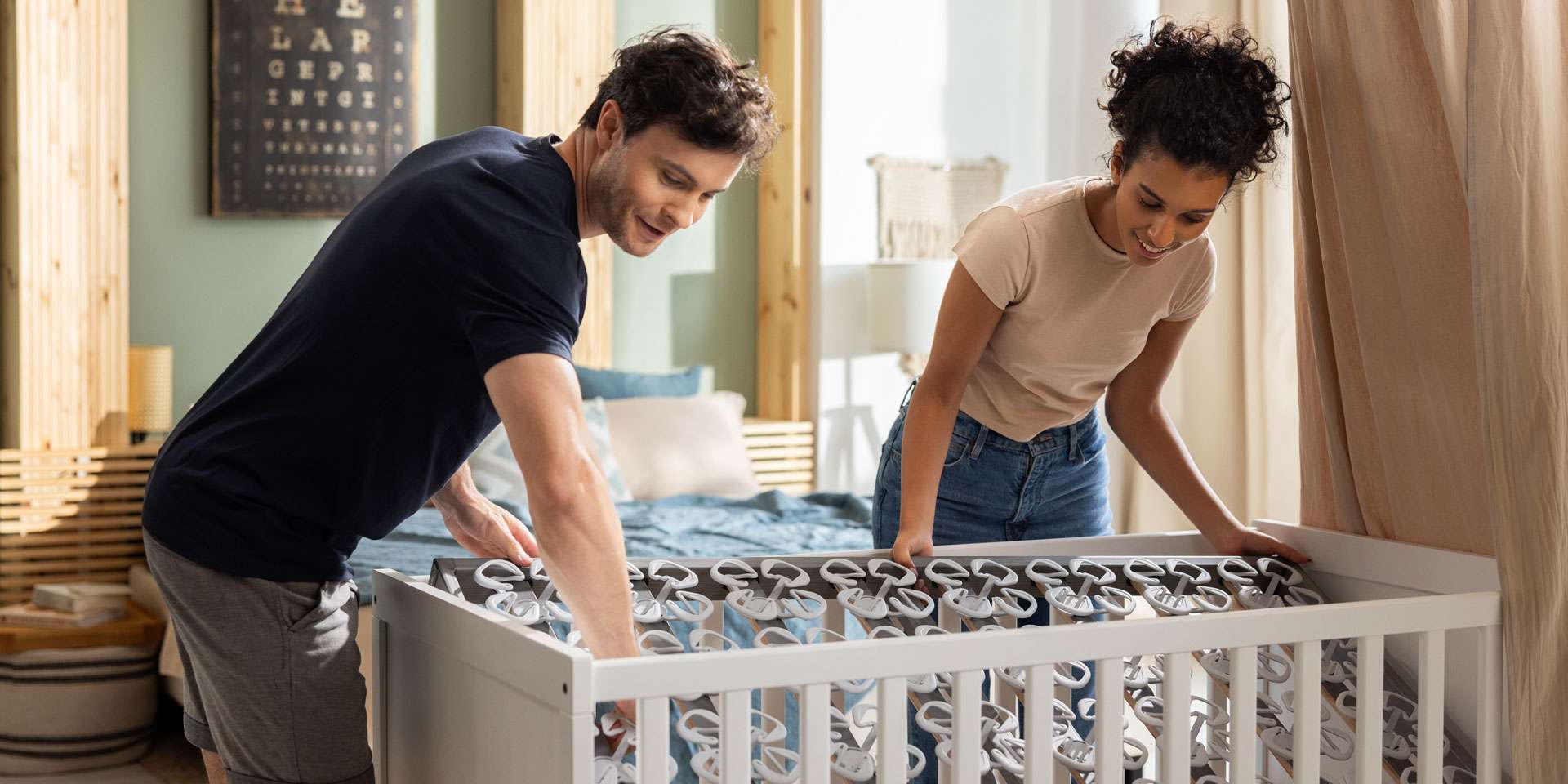 Couple sets up a crib insert in a modern bedroom.