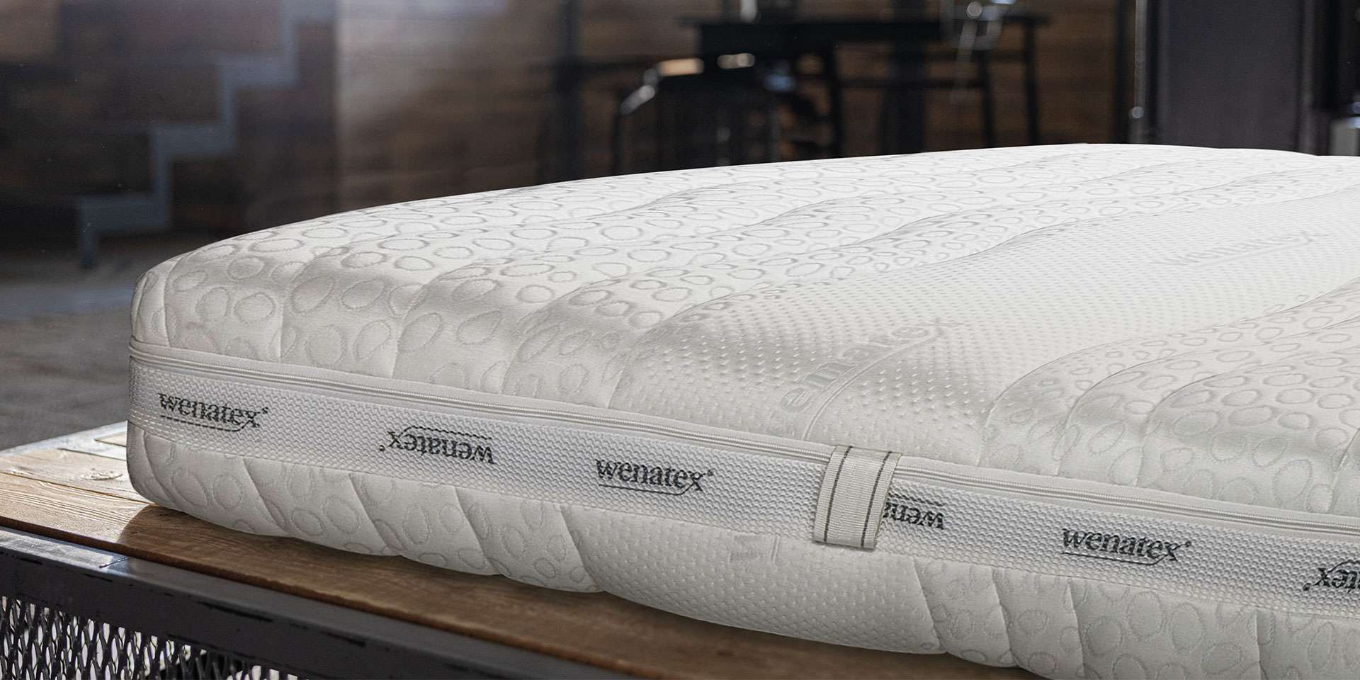 Matratze Comfort Plus von Wenatex auf einem Holzgestell, mit strukturiertem Bezug und modernem Design.