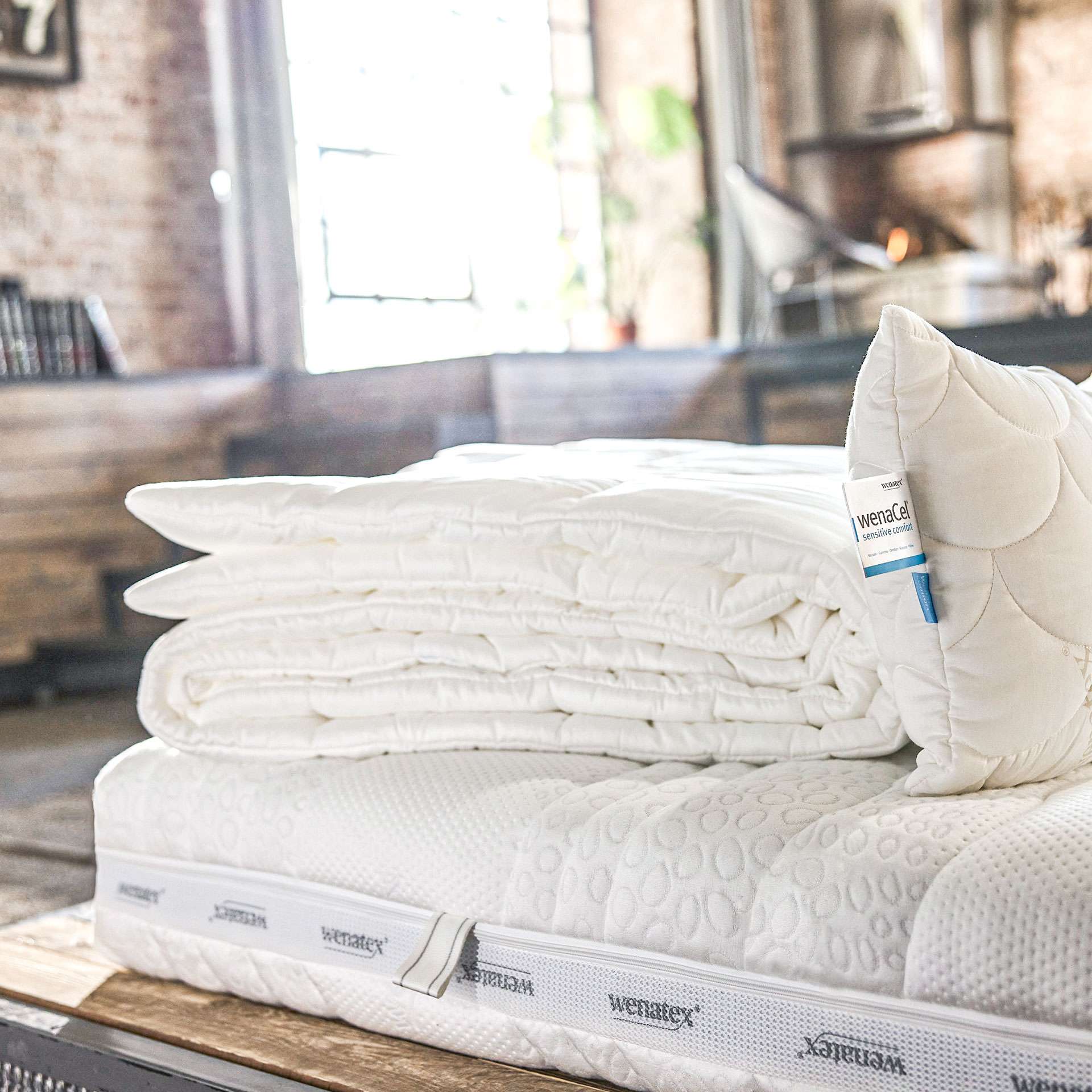 Mattress with mattress topper and pillow on a bed in a modern room.