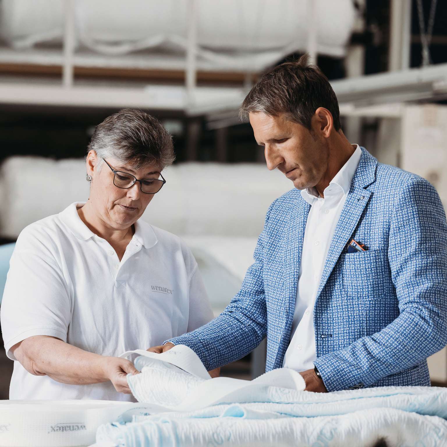 Zwei Personen prüfen gemeinsam Materialien in einer Produktionsumgebung für textile Produkte.
